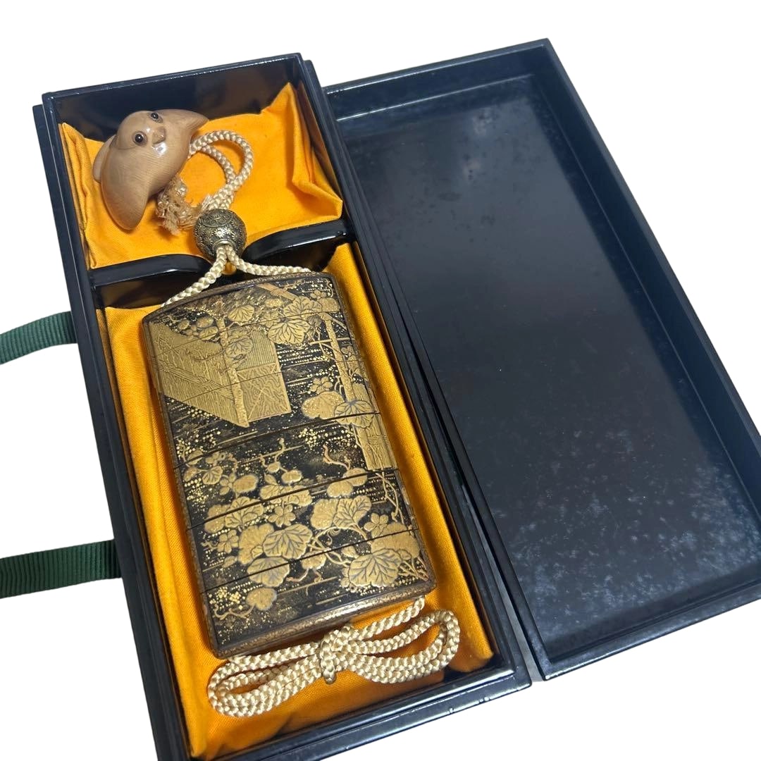 Makie Inro with Netsuke, Lacquerware: This is a black lacquered gold maki-e intricately depicting plant motifs on a six-tiered overlapping inro, accompanied by a netsuke with a bird motif. Gosho-guruma Refers to the ox-drawn carriage
