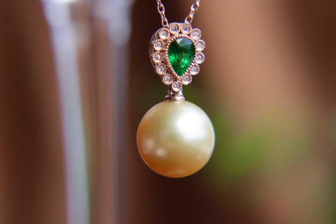 18K Gold Flawless Round Sea Pearl Pendant: This pendant is meticulously set in 18K gold, featuring a round sea pearl that radiates a strong luster and is flawless. Paired with natural tsavorite, the vibrant colors showcase a luxurious aura.