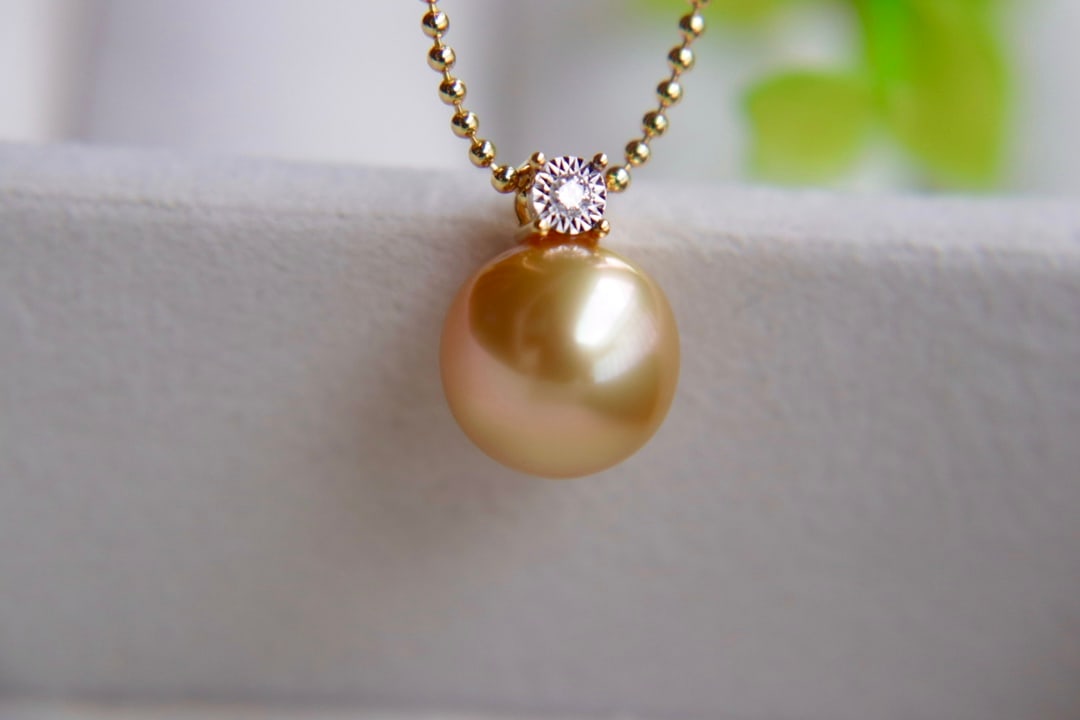18K Gold Flawless Sea Pearl Pendant: This pendant is meticulously set in 18K gold with a 10.5mm sea pearl, showcasing a strong luster and rich golden hue, flawlessly perfect, exuding unparalleled elegance.