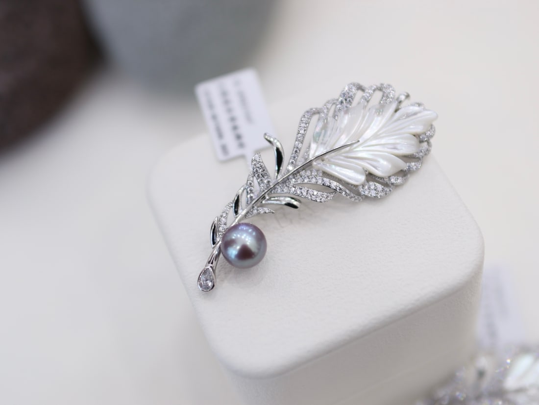 High Luster Freshwater Pearl Brooch: This brooch features a high-quality freshwater pearl in a noble and elegant purple hue. The pearl shimmers brilliantly in the light, is virtually flawless, and a slight imperfection at the base adds t