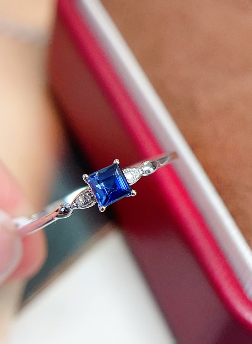18K Gold Royal Blue Sapphire Ring: This ring is crafted in 18K gold, featuring a royal blue sapphire with an elegant princess cut. Its minimalist design makes it suitable for any occasion. The ring is also adorned with 4 diamonds,