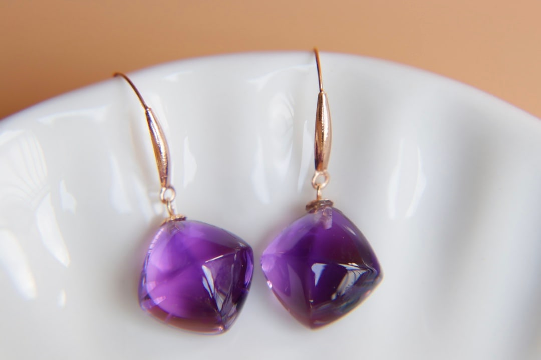 18K Gold Natural Amethyst Earrings: These earrings are meticulously crafted in 18K gold, set with natural amethyst, exuding an aura of elegance and nobility. The enchanting hue of the amethyst complements the metallic sheen, suitable