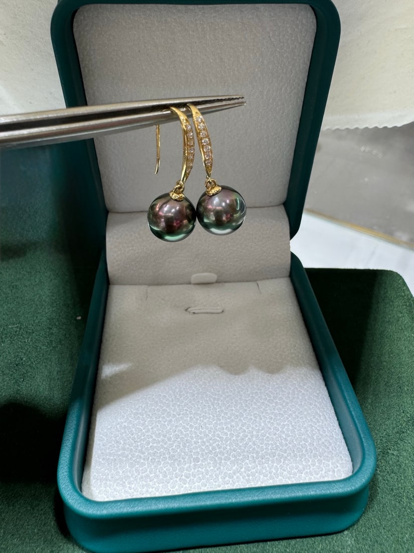 18K Gold Tahitian Black Pearl Earrings: These earrings are crafted from 18K gold and feature Tahitian black pearls, showcasing the natural luster of the pearls. The pearls are nearly round with a strong aurora effect, and minor blemishes