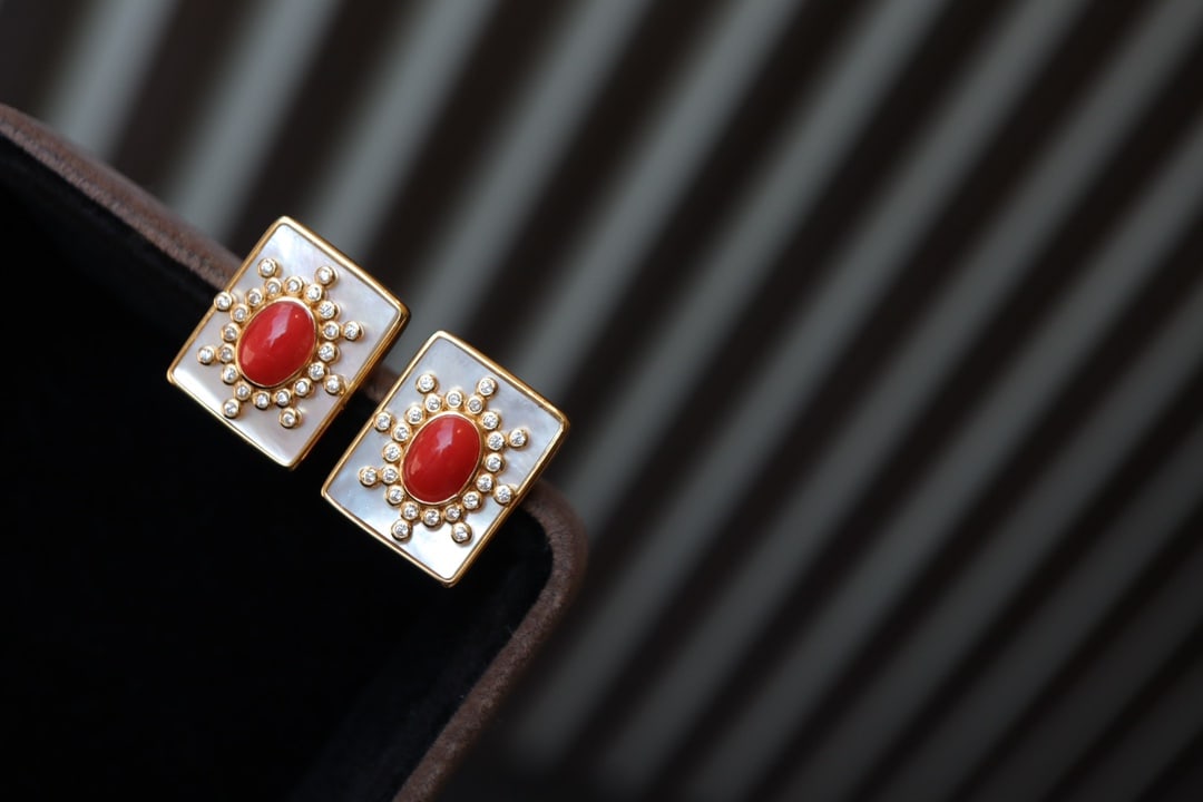 S925 Silver Natural Red Coral Earrings: These earrings feature natural red coral as the main stone, complemented by white shell inlays, showcasing a unique European and American style. The S925 silver with thick gold plating ensures lasting