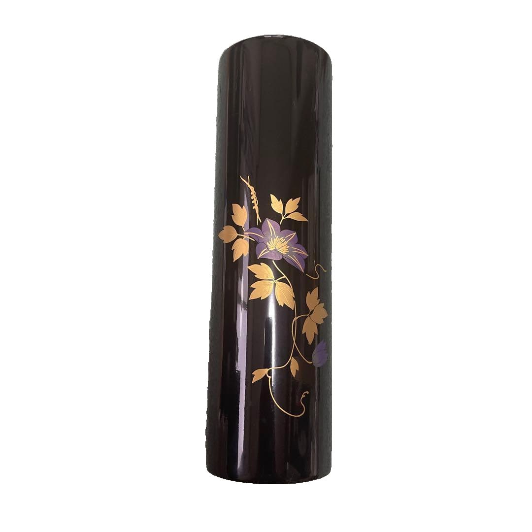 Inro with purple floral and leaf motifs adorned with gold leaf.: Inro with Purple Floral and Leaf Gold Foil Decoration A black cylindrical inro, adorned with gold foil decorations of purple flowers and leaves. Accompanied by an instruction manual. The box has