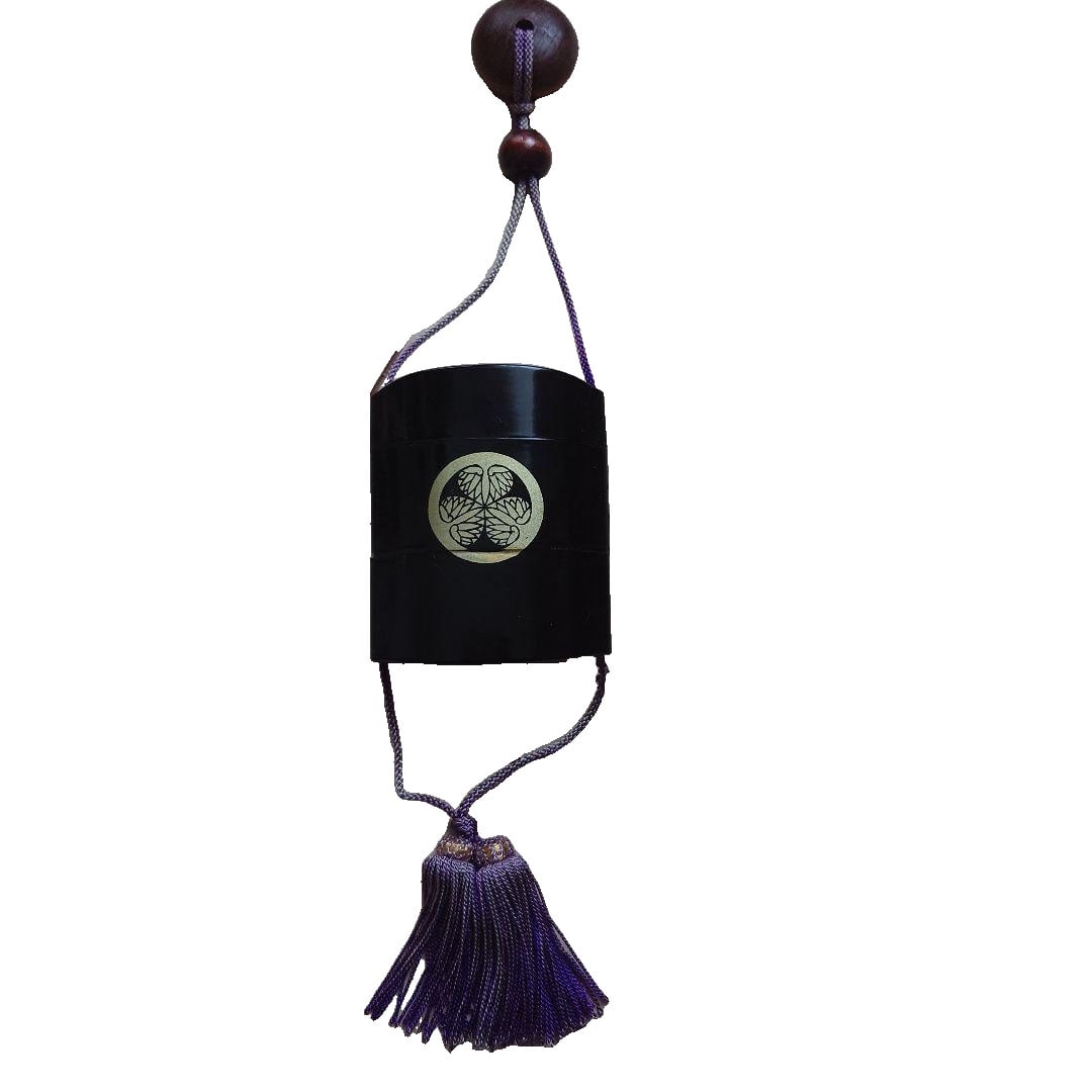 Black lacquer inro with gold patterns.: A black lacquered inro with gold patterns. The inro features gold patterns on black lacquer. It is distinguished by its purple cord and tassel. The material is lacquerware. Although there are no