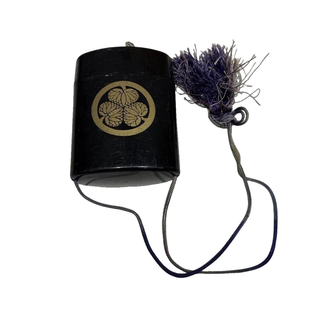 Inro by Nishiyama Sho, Black Lacquer Style, with Cord and Tokugawa Aoi Crest.: Inro Nishiyama-so Black Lacquer Style with Cord Attachment This is an inro, primarily in a black lacquer style, adorned with golden Tokugawa Aoi crests and the inscription "Nishiyama-so," accompanied