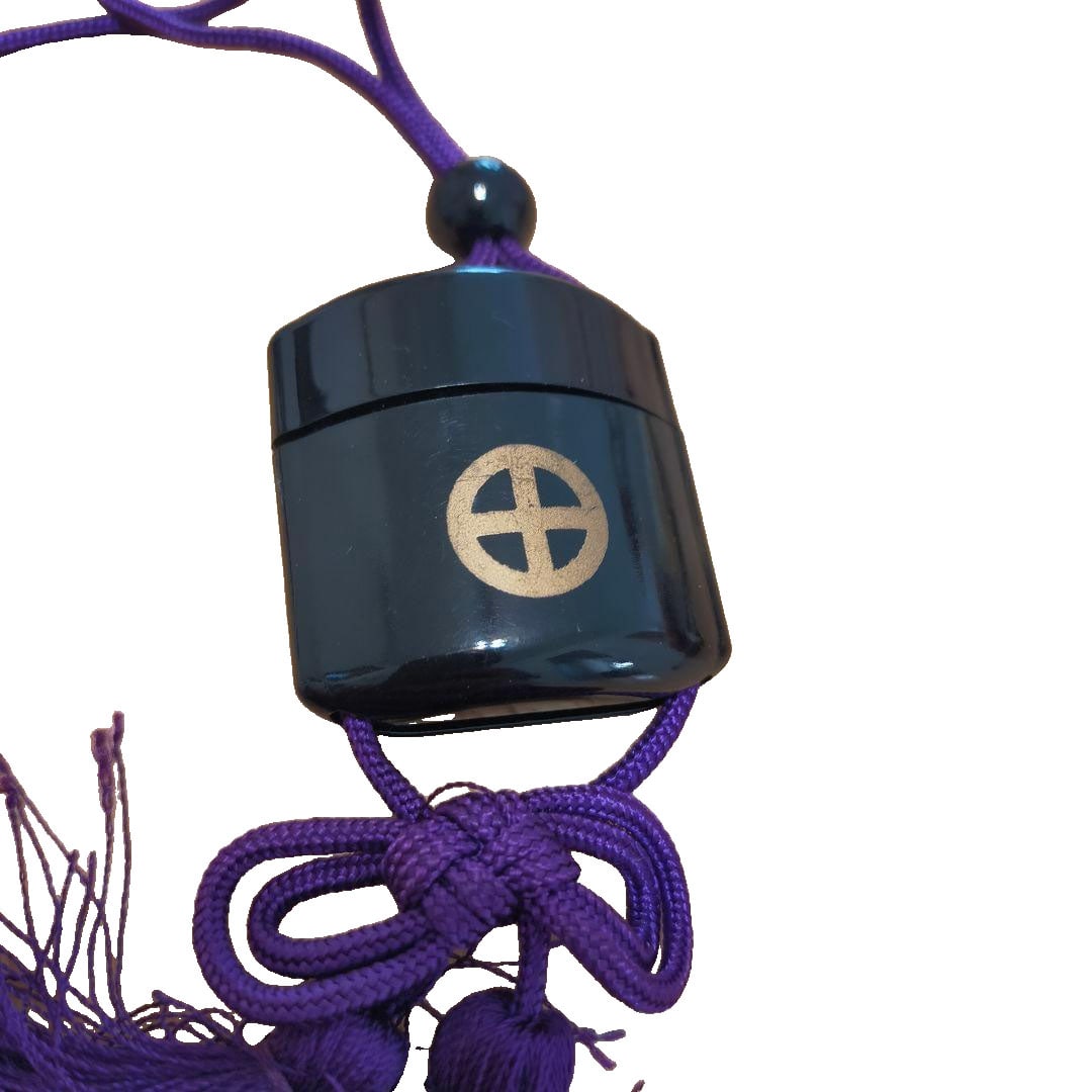 Shokoku Shrine Inro Netsuke Lacquer Black with Shimazu Clan Crest: A black lacquer inro-style netsuke featuring the Shimazu family crest from the Shokoku Shrine. Inside, it contains an oval-shaped item inscribed with "Good Luck Amulet." There are signs of wear from