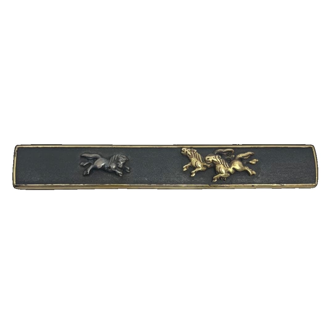 A small kozuka (handle) with a design of a mare and foal in gold on a nanako ground of shakudo.: Shakudo Nanakoji Ground with Gold Inlay Parent and Child Horse Motif Kozuka by Goto A shakudo kozuka featuring a nanakoji ground with a gold inlay depicting a parent and child horse motif, in