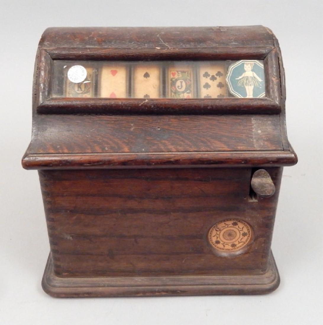 Caille Brothers oak cased penny slot machine card game: Caille Brother's oak cased penny slot machine card game, five rotating card wheels visible through slot on front, coin insert on side, lever on front, dovetailed sides, second wheel from left with mak