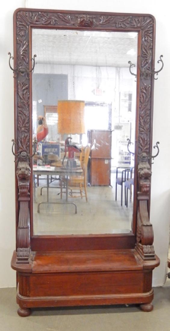 Late Victorian carved walnut hall stand: Late Victorian carved walnut hall stand, acanthus leaf and lion head carved frame around beveled mirrored back, griffin arm supports, hinged storage seat on bun feet, with hat rack hardware, 7'3" high