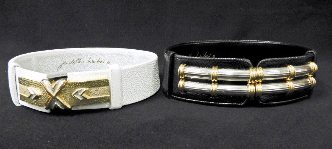 Two Judith Leiber leather belts: Two Judith Leiber leather belts, one white leather, 2 3/4" wide, wearable length 26" to 36", two part buckle in silver and gold tone buckle arrow and X design, buckle measures 4" x 1"; and one black l