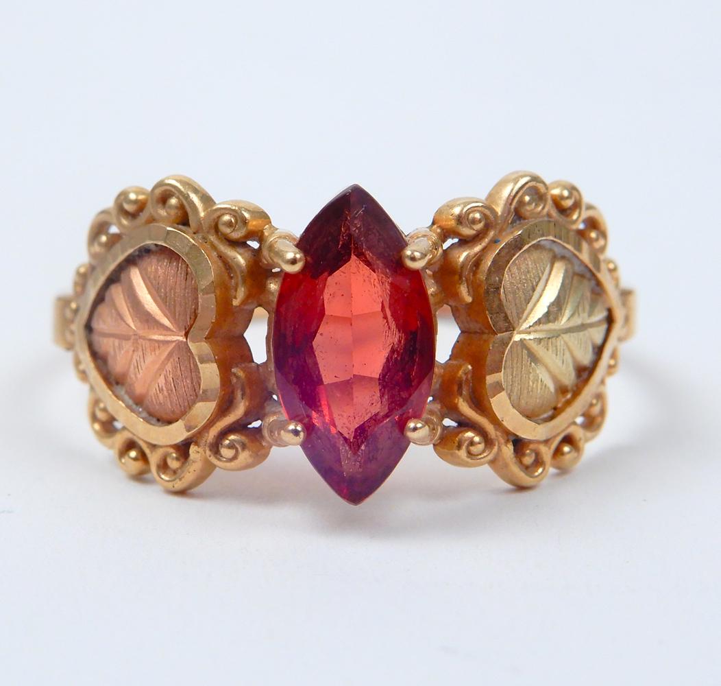 Garnet 10k Black Hills Gold type ring: Garnet 10k Black Hills Gold type ring, 10k rose and white gold mounting, navette shaped garnet measuring 9mm x 5mm with heart design on either side, size 9, stamped 10k, weight 2.5 grams/1.6 dwt