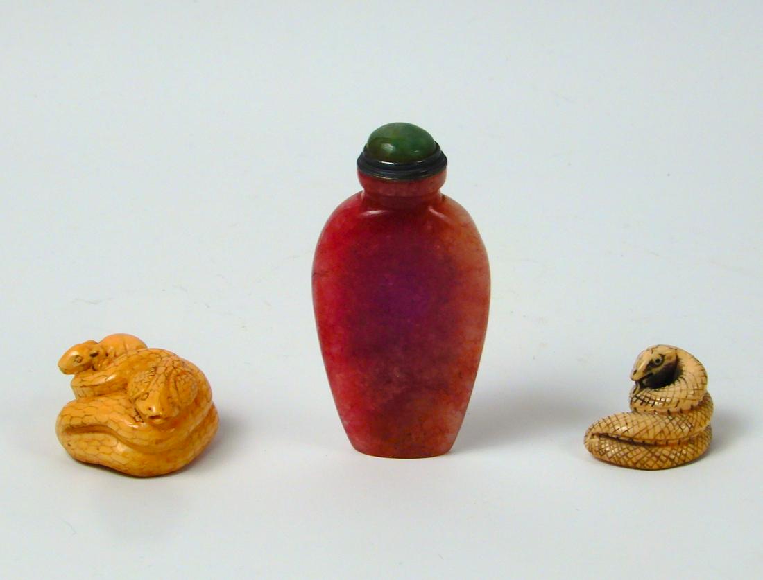 Hardstone snuff bottle and two netsuke: Hardstone snuff bottle and two netsuke, Chinese carved stone snuff bottle, rose color with green stopper, 3" high; and two Japanese carved netsuke, snakes, one 1 1/4" long and one snake with rat, 1" h