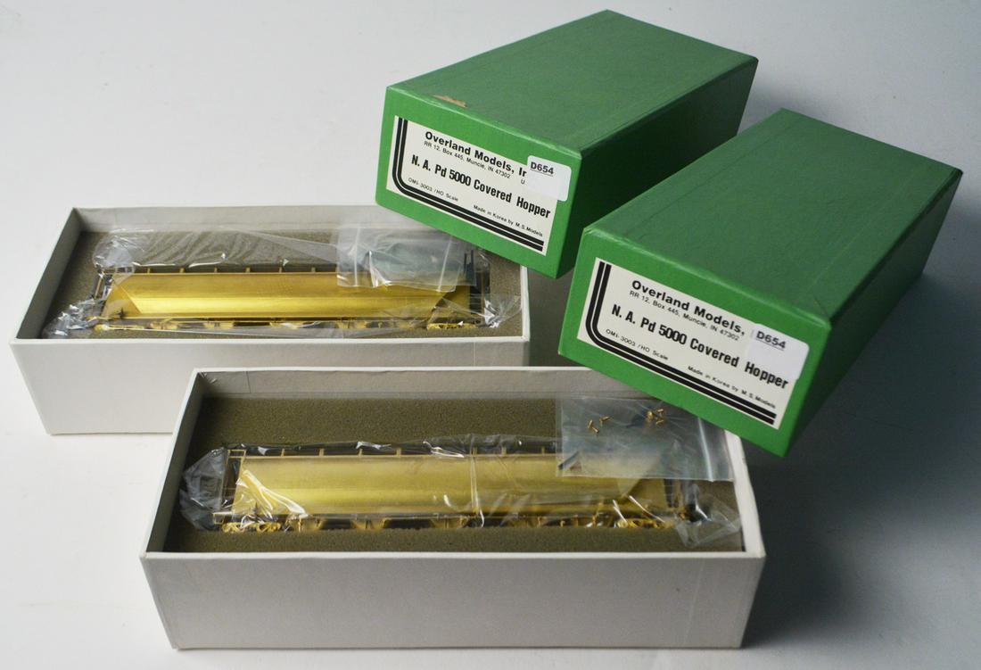 Two 1990's Overland Models by AJIN (Korea) unpainted: Two 1990's Overland Models by AJIN (Korea) unpainted brass HO gauge NA PD 5000 covered hoppers in original boxes, cylindrical hoppers. They measure about 9" long. Still sealed inside original boxes.
