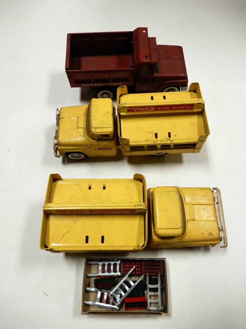 Two 1960's Buddy L Coca-Cola trucks and a 1960's: Two 1960's Buddy L Coca-Cola trucks and a 1960's Structo dump truck. All three pressed steel trucks have heavy play wear and need cleaning. The two Coke trucks have some soda crates and 4 hand trucks.