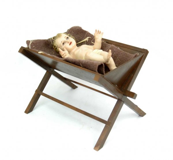 Plaster figure of Christ child, 13" long, brown gl: Plaster figure of Christ child, 13" long, brown glass stationary eyes, open mouth with teeth, with wooden manger 11" high x 18" long x 12" deep