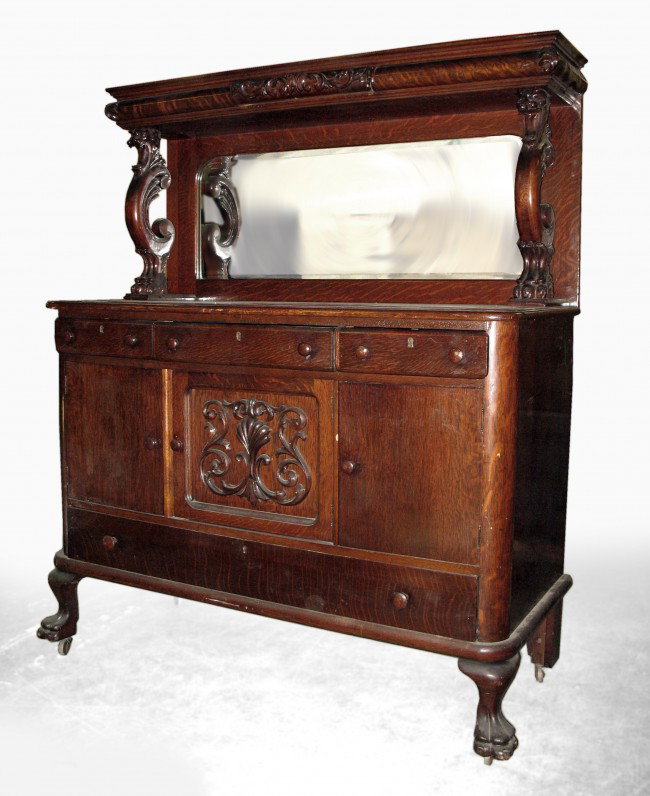 Oak sideboard, two piece, molded cornice with appl: Oak sideboard, two piece, molded cornice with applied decoration, mirrored splashback, lion head and paw foot supports, base with three short drawers over three cabinet doors, the center door with app