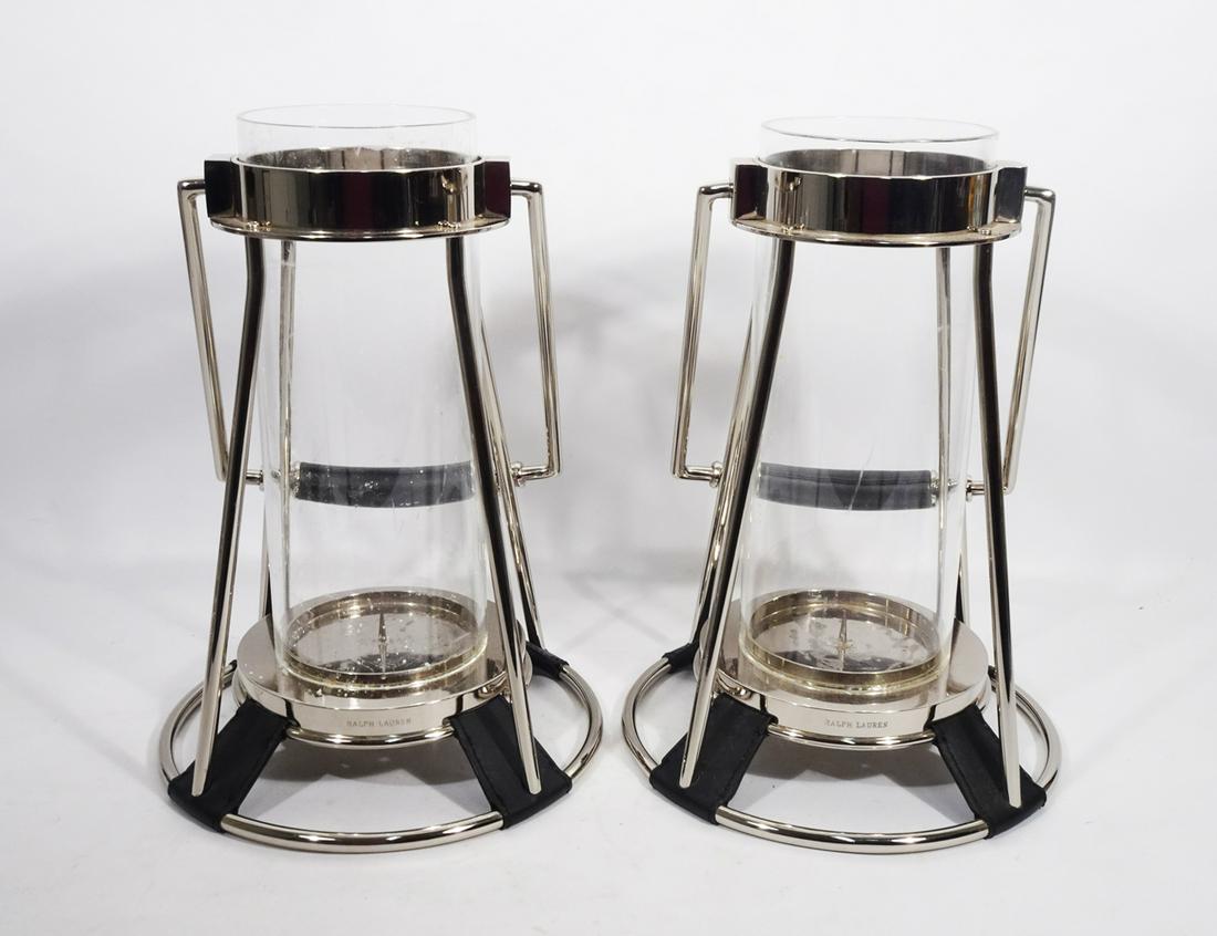 Pair of Ralph Lauren Candle Hurricanes: Pair of Ralph Lauren candle hurricanes, nickel silver finish with glass tube from shades, black leather strap on handles and black leather mounts on base, contemporary 21st c., signed along candle bas