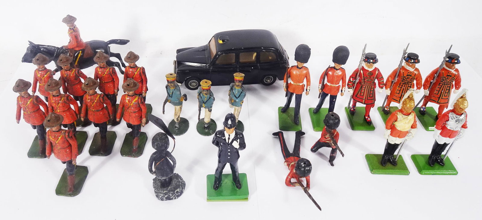 Vintage Britain's metal figures and a Budgie London taxi.: Vintage Britain's metal figures and a Budgie London taxi. There are 9 marching Canadian Mounties (1 with no arm), a mounted rider, 3 French Foreign Legion (1 with broken gun, 2 older black watch and 8