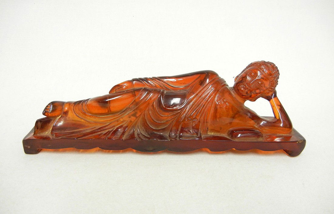 Carved cherry amber reclining Buddha, good luck sym: Carved cherry amber reclining Buddha, good luck symbol on chest, 2 1/2" high x 8 1/2" x 2"