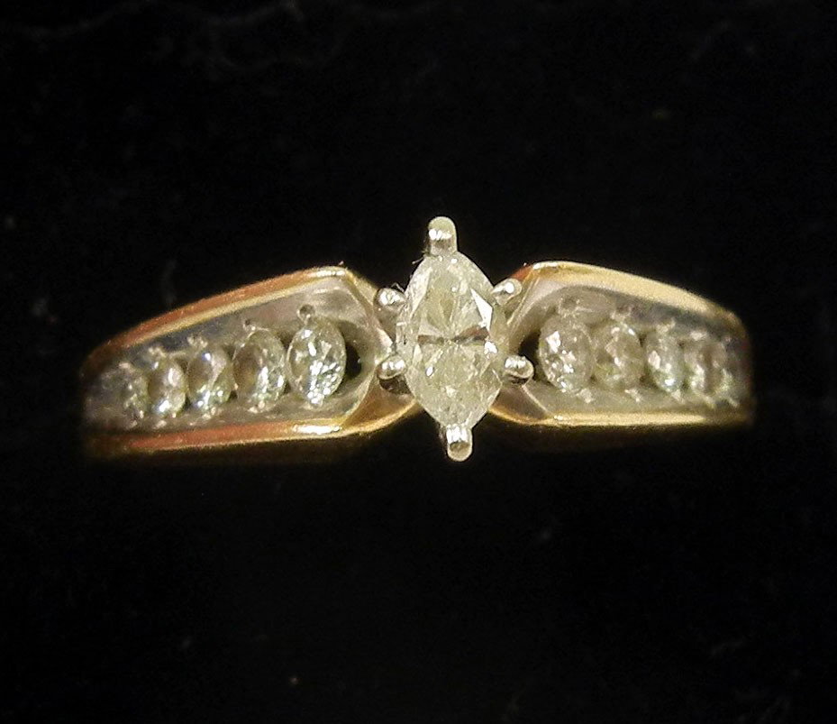 Gold and diamond solitaire engagement ring, center: Gold and diamond solitaire engagement ring, center marquise cut diamond measuring approximately 15 points with five graduated channel set round diamonds on either side, side stones range from 1-4 poin