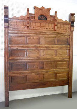 Paneled oak highback headboard, carved crest with: Paneled oak highback headboard, carved crest with winged cherub, late 19th C., 86" high x 65"