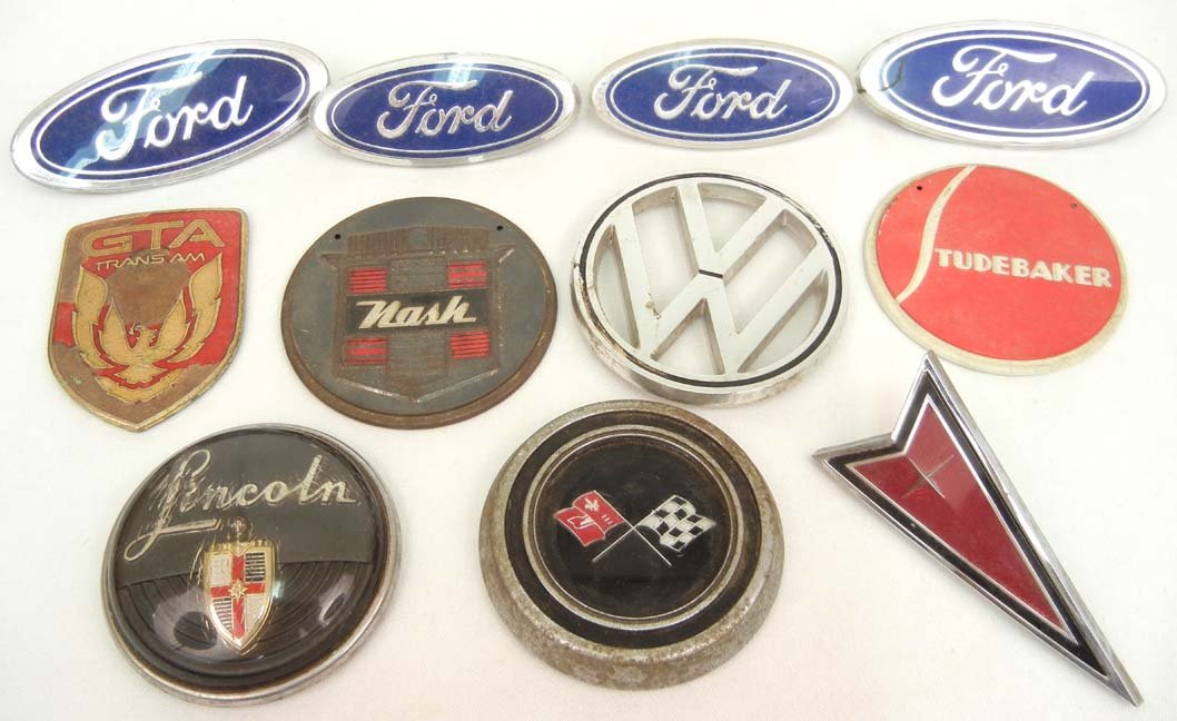 Grouping of eleven vintage automobile emblems incl: Grouping of eleven vintage automobile emblems including Ford, Volkswagen, Nash, Studebaker, GTA Trans Am, Pontiac, Lincoln, and Corvette