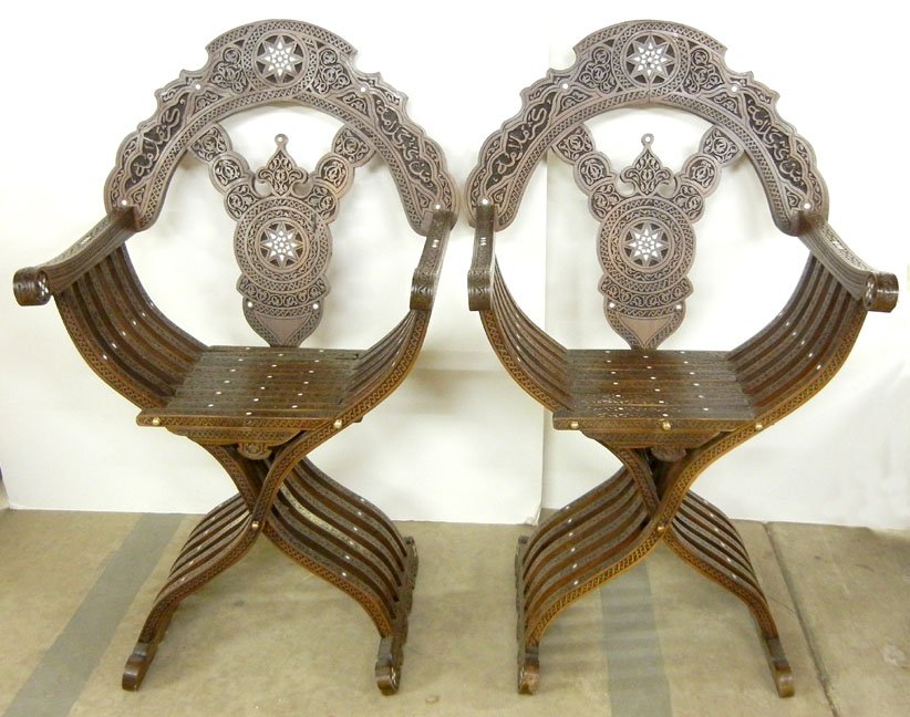 Pair of inlaid Middle Eastern curule chairs, ornat: Pair of inlaid Middle Eastern curule chairs, ornate carving overall, mother of pearl inlay, mid to late 20th C., 43" high x 25" x 15"