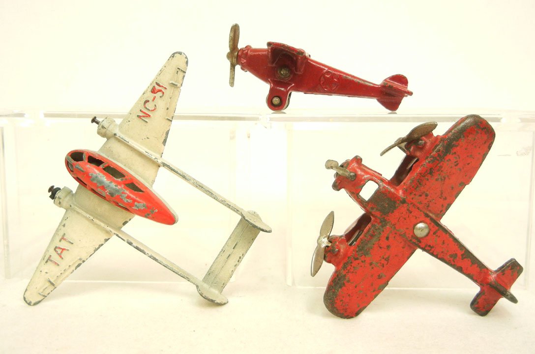 Three cast iron and aluminum airplanes, one with s: Three cast iron and aluminum airplanes, one with star in circle on both sides of plane body, one trimotor plane with medallion in center of bottom, and a Hubley TAT NC-31