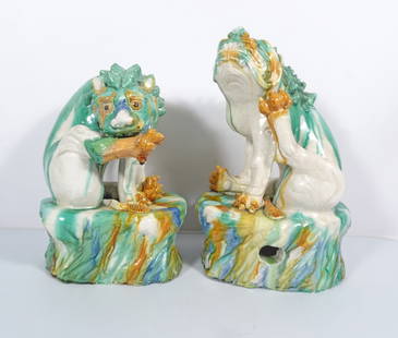 Pair of Chinese Sancai Glazed Ceramic Foo Dogs: Pair of Chinese multi colored Sancai glazed ceramic foo dog figures, both are seated on a naturalistic style oval base, the other with his left hind leg lifted to scratch his face, both are unsigned,