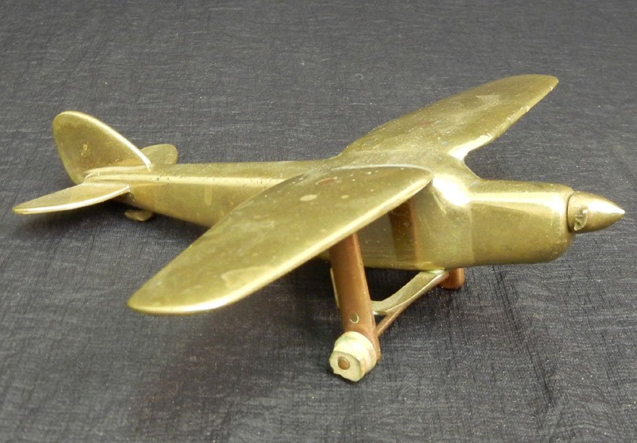 Trench Art High Wing aircraft model, aluminum and brass: Trench Art High Wing aircraft model, aluminum and brass, made from brass bullets and casings and scrap metal in the field during WWII and later by soldiers and mechanics, 6 3/8" wing span, 6 1/2" long
