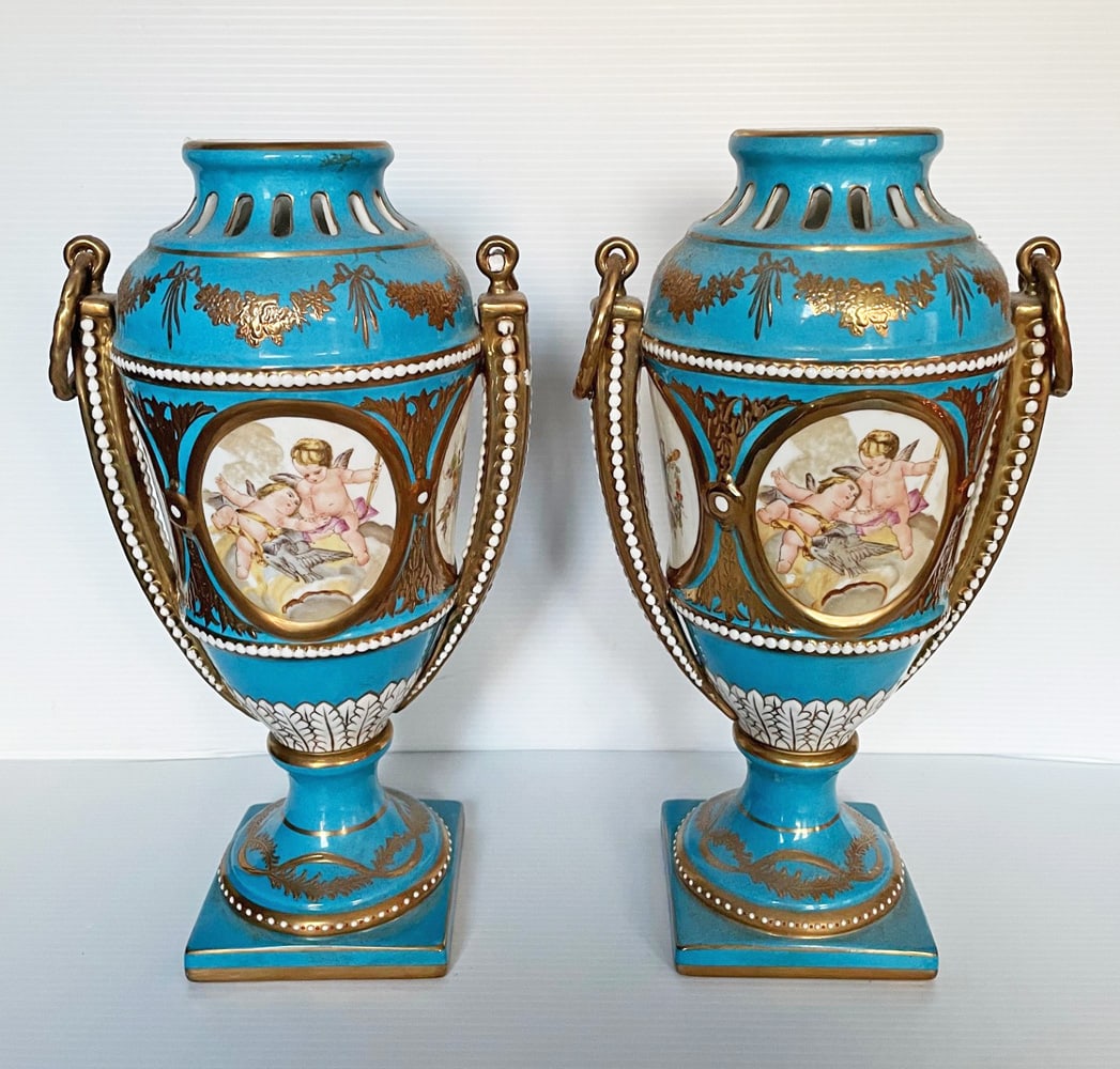 Pair of Porcelain Mantle Urns: Pair of porcelain handled mantle urns, cartouches with winged cherubs on front and back, enameling and gilt decoration, unmarked, 14" high