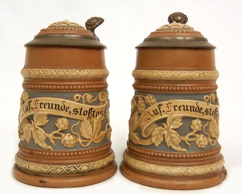 Two Mettlach German pottery steins #1740, 1/4L, floral : Two Mettlach German pottery steins #1740, 1/4L, floral design, "Auf, Freunde, Stokton" across front, inlaid lid, both impressed marks on bottom, ca. 1903, 6 1/4" high