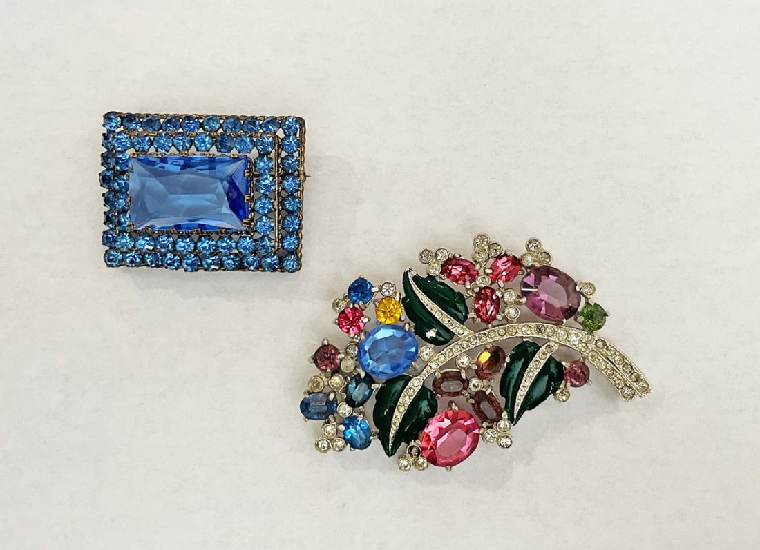 Two Vintage Rhinestone Pins: Two vintage rhinestone pins, one blue with large center stone, with two tiers of smaller stones, 1 1/2" x 1 1/8", stamped Czechoslovakia; and one silver tone metal floral design with multicolor rhines