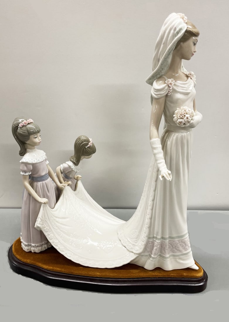 Lladro Here Comes the Bride Porcelain Figurine: Lladro Here Comes the Bride Porcelain Figurine with base, depicts a bride with bouquet and two flower girls holding her dress, marked on bottom, number 1446, figurine measures 13 3/4" high x 6" wide x