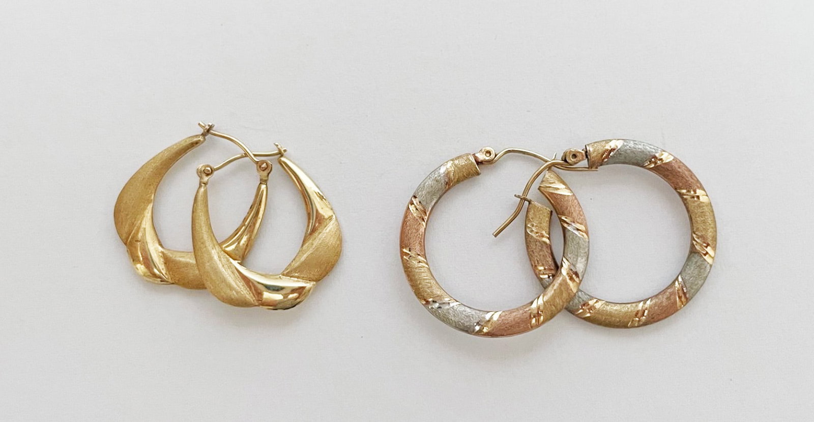 Two Pairs of Gold Hoop Earrings: Two pairs of gold hoop earrings, one pair of round 10k tri-color gold, 1" long, weight 1.3 grams; and one pair of oval shaped 14k yellow gold, 7/8" long, weight 1.1 grams