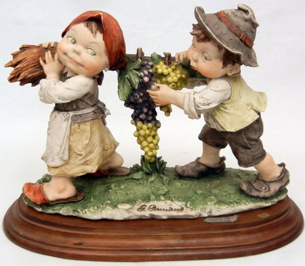 Giuseppe Armani figurine, Gulliver's World, boy and gir: Giuseppe Armani figurine, Gulliver's World, boy and girl carrying grapes on a broom, stickers on front, signed on front, 8 1/4" high x 11 1/2" across