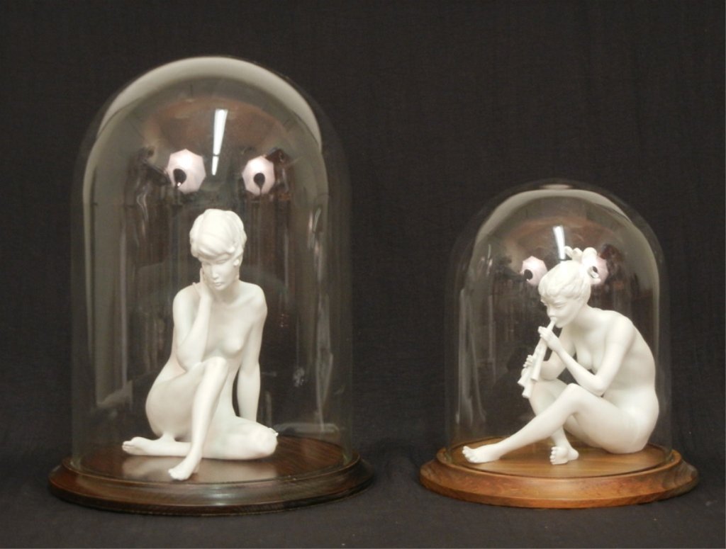 Two Kaiser figurines, "Meditation" No. 489, 9"; and "Gi: Two Kaiser figurines, "Meditation" No. 489, 9"; and "Girl with Flute" No 385, 7 1/4", each marked on bottom and both with E&R foil labels, both with glass dome cases 11 1/2" and 15 1/2"