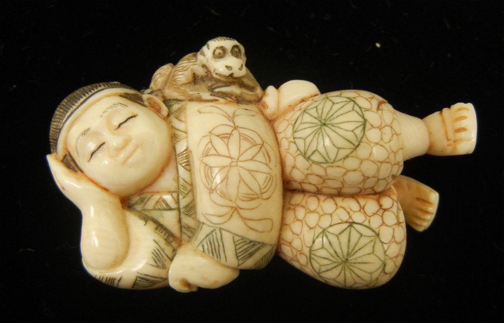 Hand carved ivory netsuke: Reclining boy with monkey, 2" long, hand colored, signed on foot