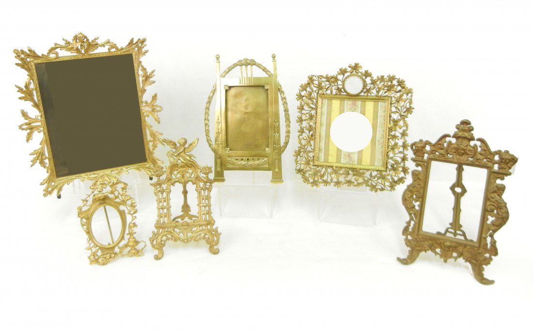 Six ornate brass picture frames: Six ornate brass picture frames, largest with cherub and bird at top, 14", one floral with round beveled glass at top, 10 1/4", marked Globe on back, one with mask at top and bottom, telamon on either