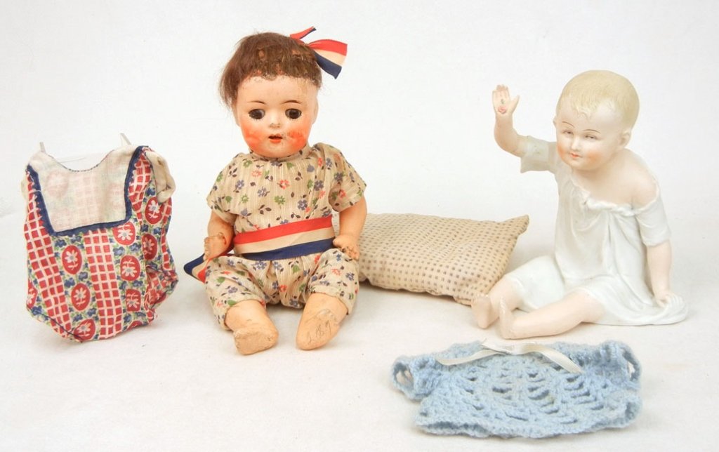 Bisque head doll and a piano baby: Two dolls, including a bisque head composition doll, 10", brown glass eyes, painted lashes, open mouth with two upper teeth, head impressed "24", and a German bisque piano baby, sitting with flower on