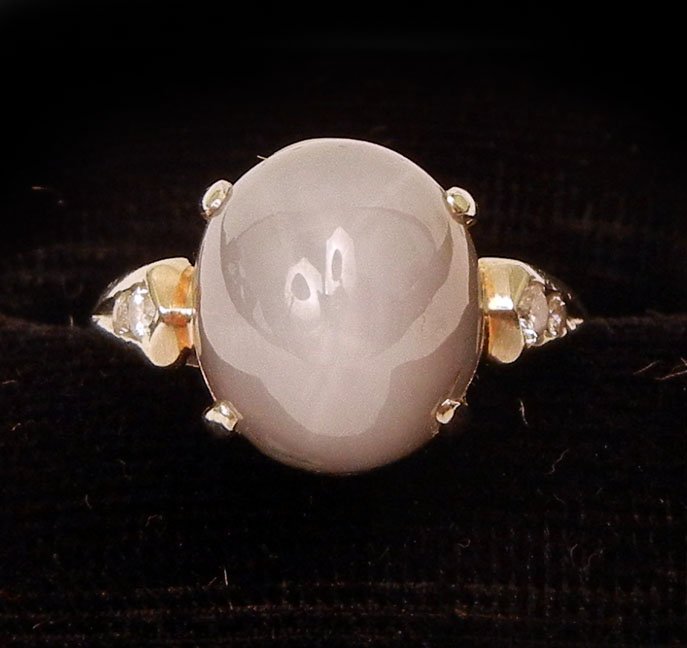 Gold star sapphire ring: 14k white gold ring with oval cabochon blue star sapphire measuring 10mm long x 8mm wide x 8mm high, two diamonds on either side measuring 0.02 carats and 0.04 carats each, size 2 1/2, marked 14k, wei