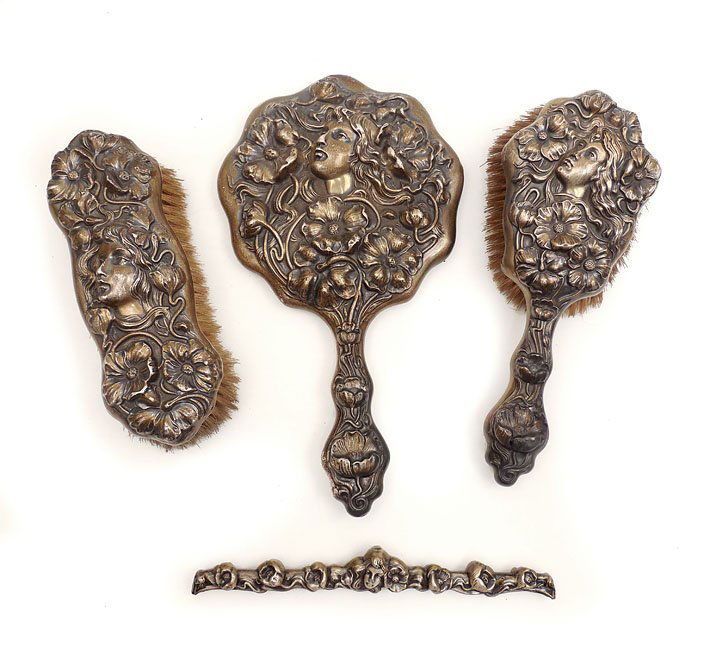 Art Nouveau sterling silver dresser set: Four piece Art Nouveau sterling silver dresser set with woman's face and flowers includes hand mirror 10 1/4" long, hair brush 8 1/2" long, clothes brush 7" long, and frame for hair comb, 7 1/2" long,