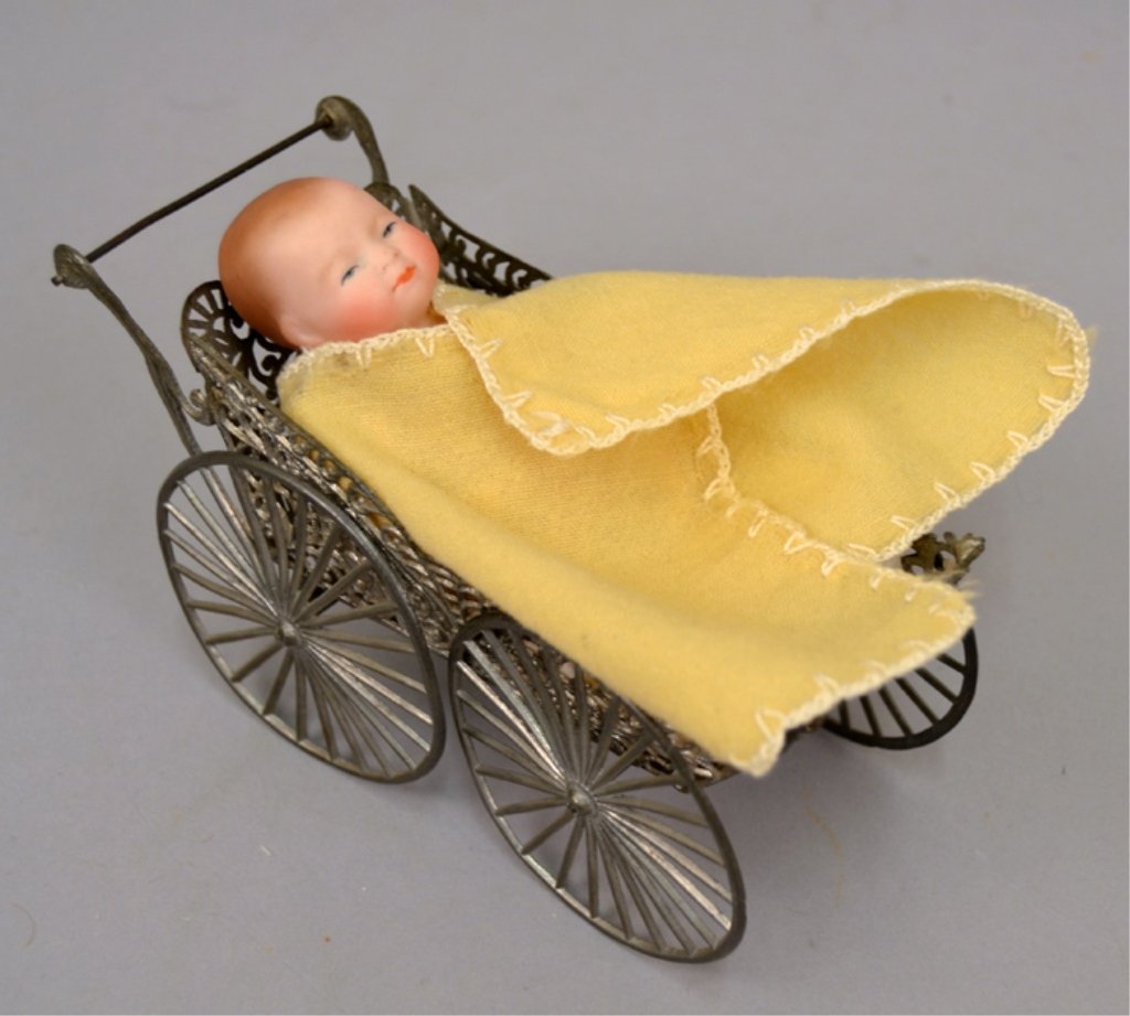 Antique bisque bye-lo baby in German soft metal: Antique bisque bye-lo baby in German soft metal carriage, 4" all bisque jointed doll by Grace S. Putnam, painted eyes and mouth, wearing dress, marked on back "20-10, Copr. By Grace S. Putnam, Germany