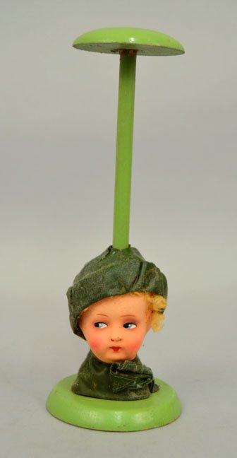 German antique doll hat stand: German antique doll hat stand, paper mache doll head, painted features, with green hat and scarf, on a green painted wooden stand, stamped on bottom Germany, 9 1/4" high