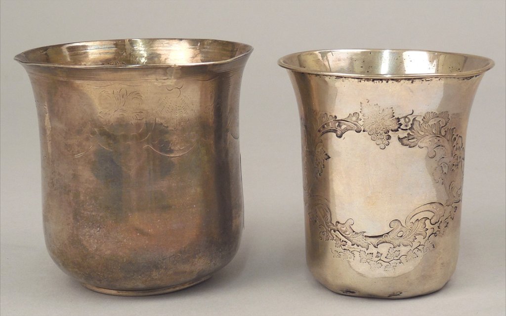 Two silver beakers: Two silver beakers, one German silver, slightly flared rim, chased design with open cartouche, winged cherubs holding grapes, scrolls, acanthus and grape leaves, marked on bottom with "13" in square, 