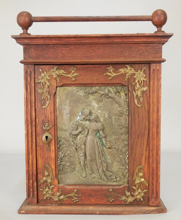 Oak hanging cabinet: Oak hanging cabinet with copper figural panel, applied brass foliate spandrels, with stick and ball gallery, 16 1/2" x 12 1/2" x 3 1/2"