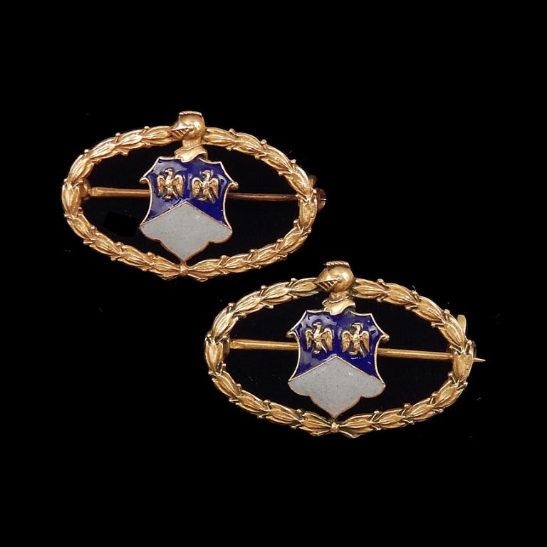 Two gold enameled pins: Two 14k gold enameled organizational pins, shield and knight's helmet motif with blue and white enameling, each 1" long x 5/8" wide, stamped 14k J.E.C. & Co. (J.E. Caldwell Company), one is engraved o