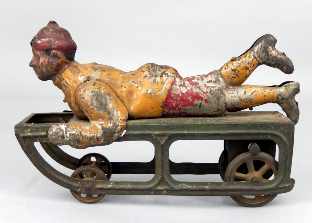 Dayton Boy on Sled, friction toy: Dayton Boy on Sled, friction toy, tin painted figure on sled, painted with red hat and pants, yellow jacket and socks, green sled, and yellow spoke wheels, friction motor, 9 1/8" long, Collection of J